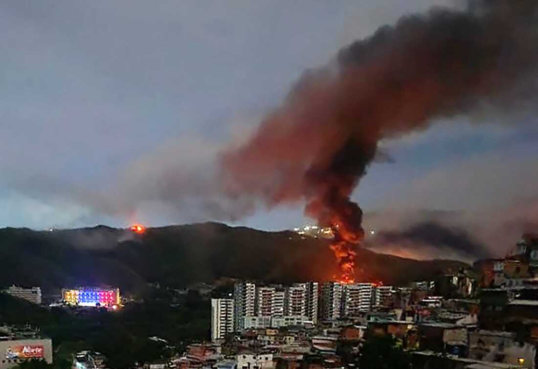 Fire at Fuerte Tiuna, Venezuela's largest military complex, is seen from a distance after a series of explosions in Caracas on January 3, 2026. The United States military was behind a series of strikes against the Venezuelan capital Caracas on Saturday, US media reported. The White House and Pentagon have not commented on the explosions and reports of aircraft over the city. US media outlets CBS News and Fox News reported unnamed Trump administration officials confirming that US forces were involved. (Photo by AFP)