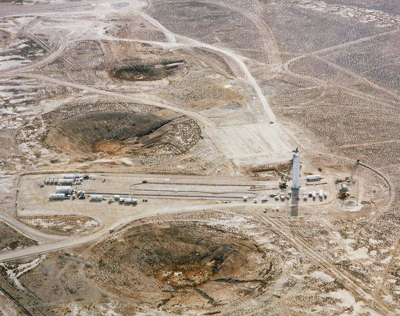 ^BNuclear test preparation.^b Aerial view of prepara- tions for an underground atomic bomb test in Nevada, USA. A rack containing detectors which will be placed underground has been assembled in the tower at right. Many kilometres of cable carry data from these detectors to instrumentation in the trailers at left. Saucer-shaped craters caused by subsidence after previous underground nuclear explosions lie around the test site. The craters vary is depth and diameter, depending upon the weapon's size and burial depth, as well as the geology of the area immediately around it.