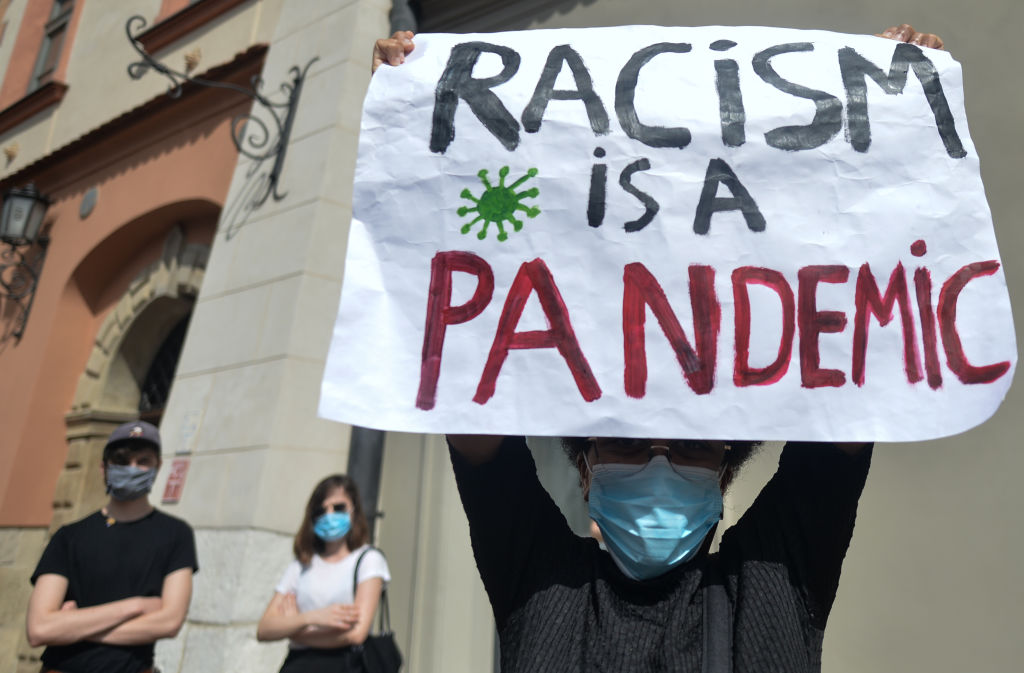 A participant of a march in memory of George Floyd holds a 'Racism Is A Pandemic' sign.On May 25 in Minneapolis, 46-year-old black man George Floyd was strangled by a police officer. Many residents and foreigners turned out today in Krakow to express their solidarity with Floyd's family, loved ones and with hundreds of thousands of Americans who have been coming out on the streets of their cities for several days, demanding justice. On Sunday, June 7, 2020, in Krakow, Poland. (Photo by Artur Widak/NurPhoto)
